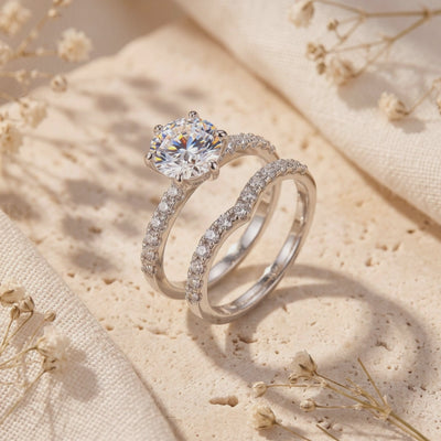 Sterling silver round solitaire ring and curved pavé nesting band displayed upright on a beige textured stone block.