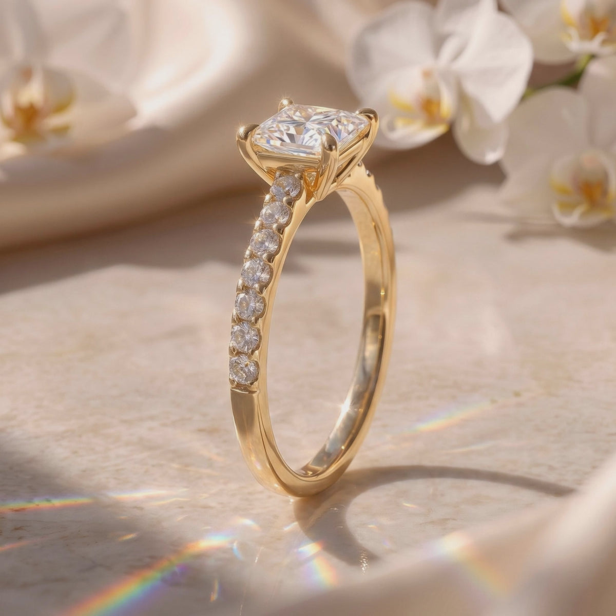 Angled side view of a yellow gold-tone pavé solitaire ring with a four-prong princess-cut center stone.