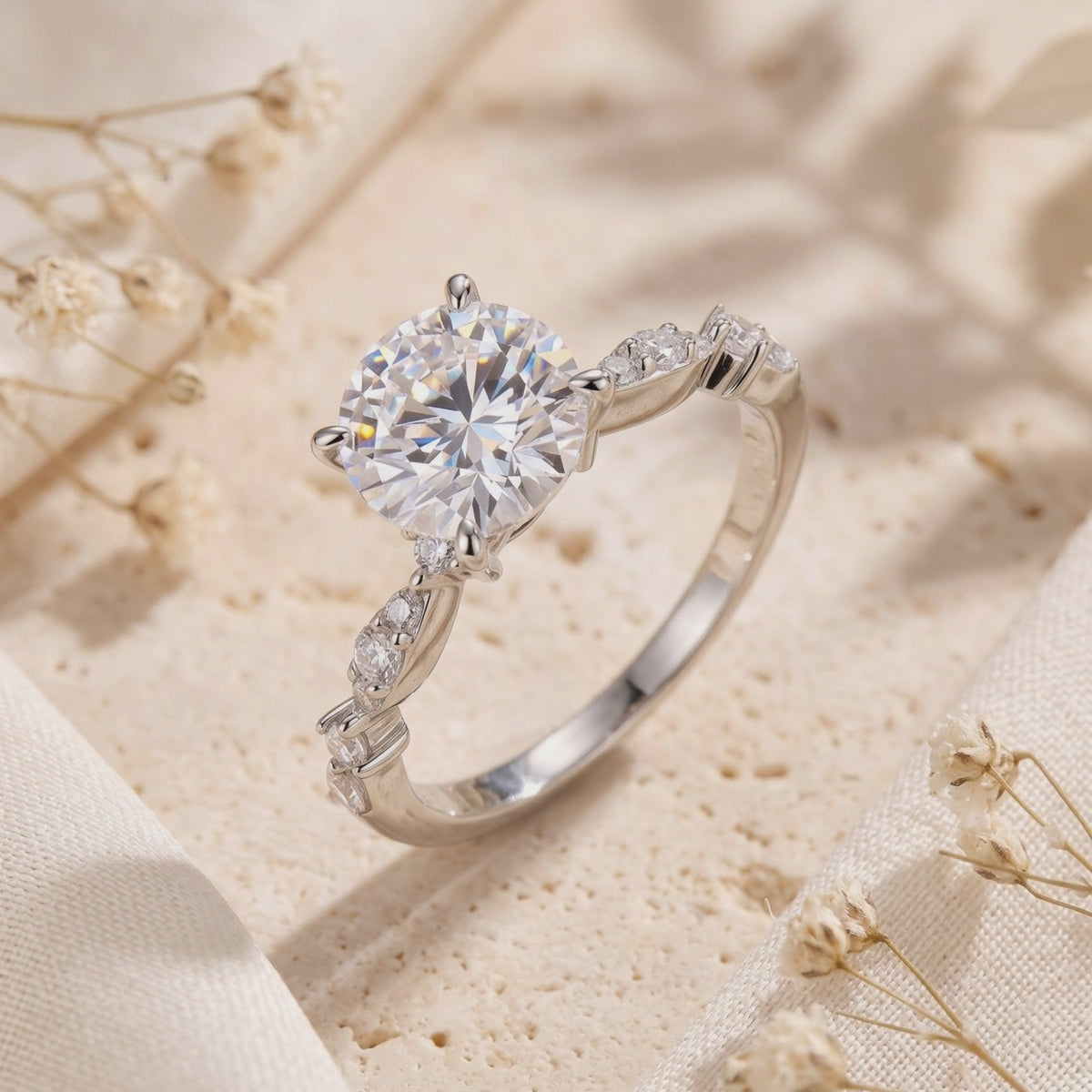 Close-up angled view of the silver solitaire ring resting on a textured surface with dried flowers.