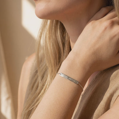 Silver-toned bar bracelet engraved with Roman numerals, worn on a woman's wrist.