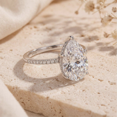 Silver Dianora ring with pear-cut stone and visible S925 stamp resting on a textured stone surface.