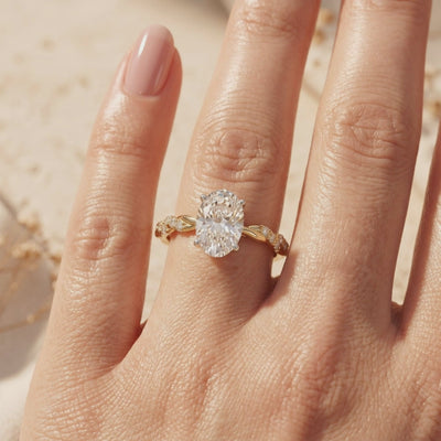 Gold-toned Lysandrielle ring with an oval center stone and twisted pavé band worn on a hand.