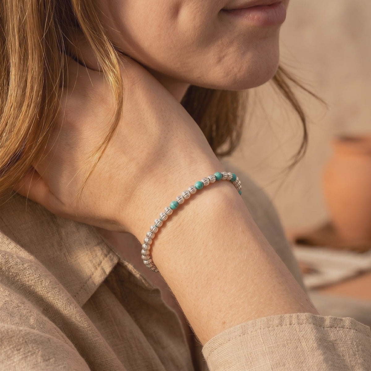 Model wearing the Pecos turquoise bracelet with ribbed silver beads and teal turquoise accents on her wrist.