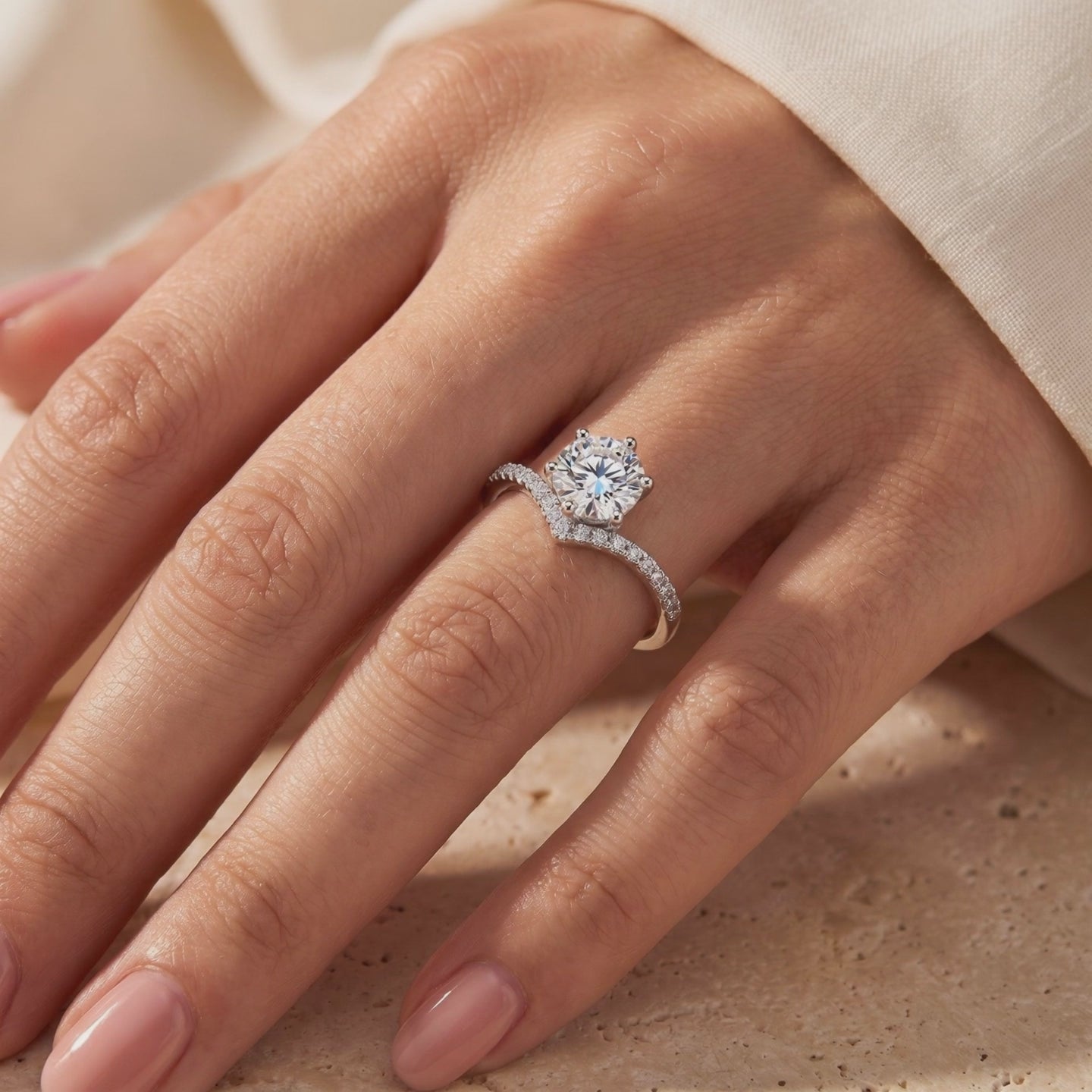 Silver chevron ring with a round center stone and micro-pavé band worn on a finger.