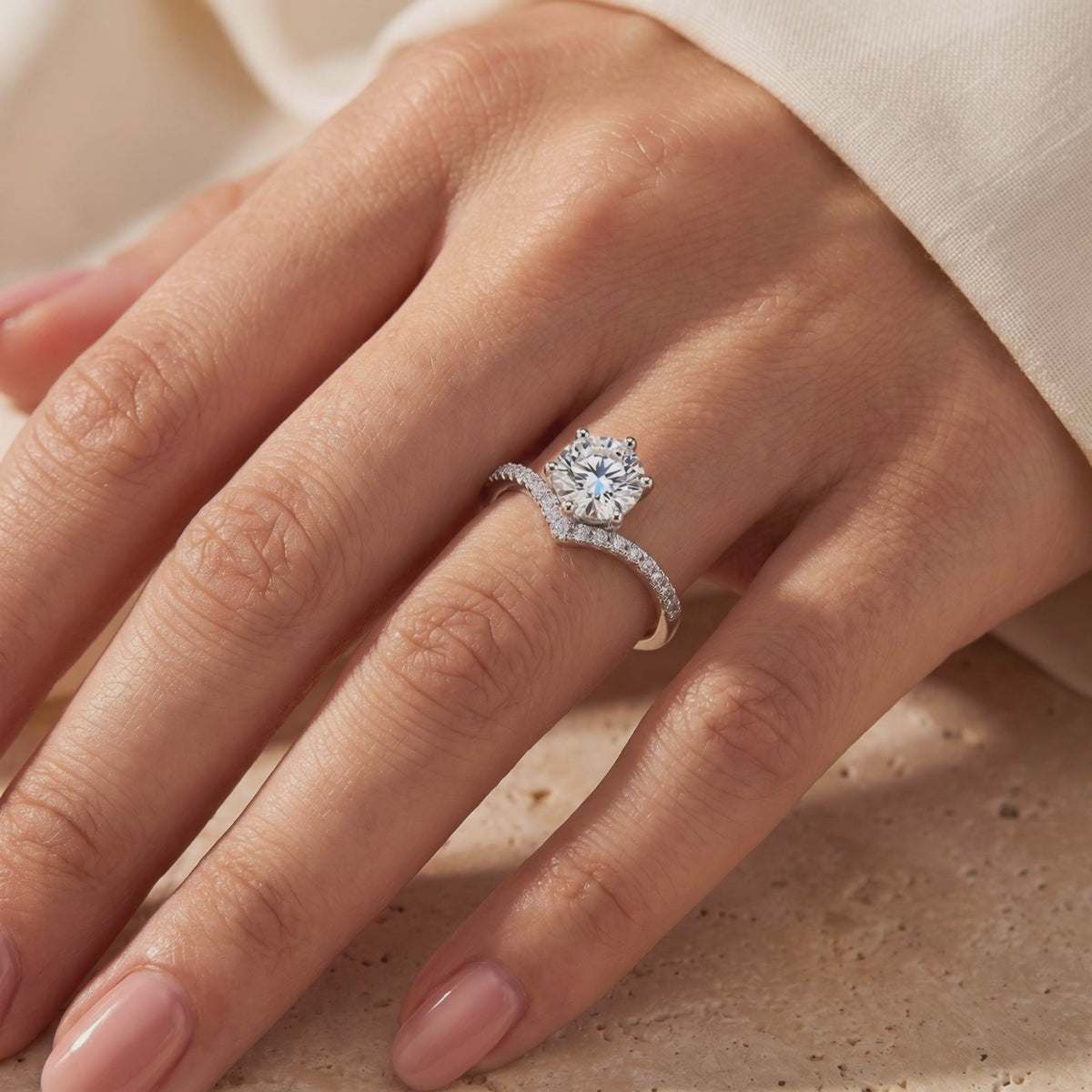 Silver chevron ring with a round center stone and micro-pavé band worn on a finger.
