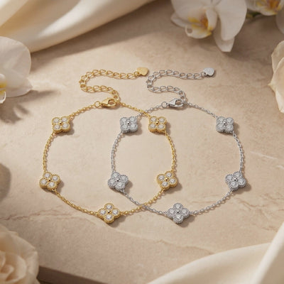 Gold and silver moissanite clover bracelets displayed flat with extender chains on a stone surface.