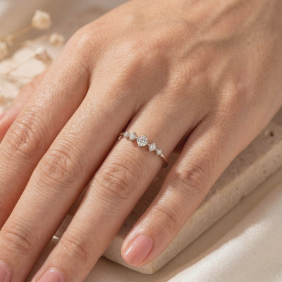 Elysand silver ring with five graduated moissanite stones worn on a hand, with dried flowers in the background.