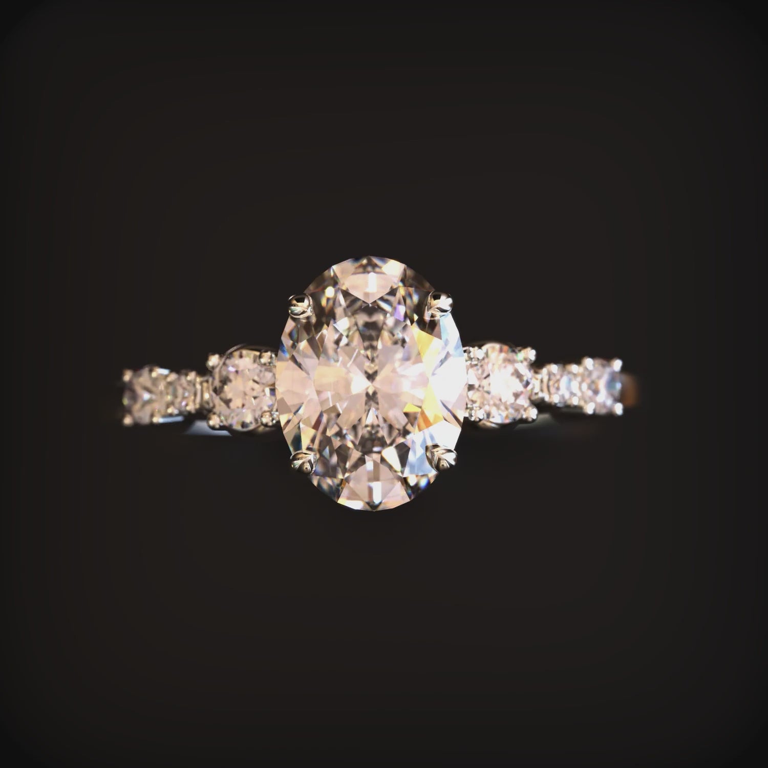 A solid gold ring with an oval moissanite center stone and round side stones.