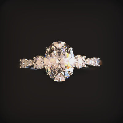 A solid gold ring with an oval moissanite center stone and round side stones.