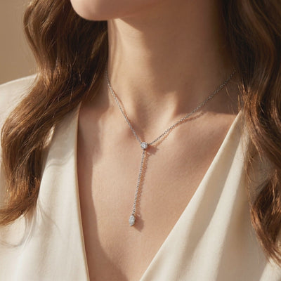 Silver-tone moissanite lariat necklace with a round stone at the junction and a dangling marquise drop, worn on a model.