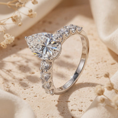 Angled close-up of the silver pear-cut ring displaying accent stones and inner band S925 stamp.