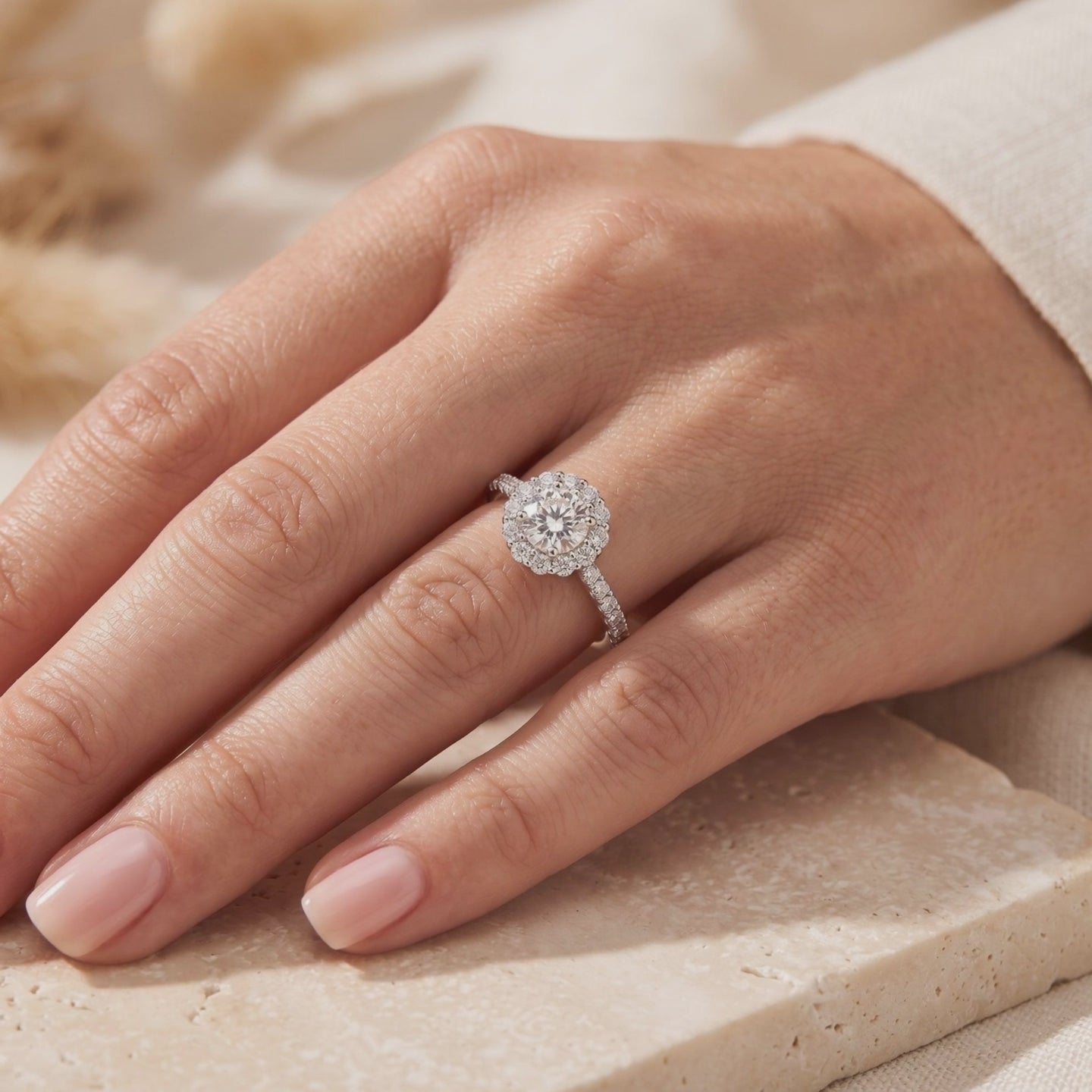 Video frame showing a person wearing the silver-colored round halo ring with a floral setting and pavé band.