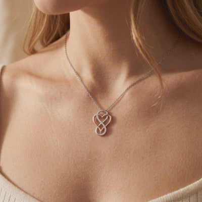 Model wearing a two-tone infinity-heart pendant necklace with a pavé stone-accented loop.