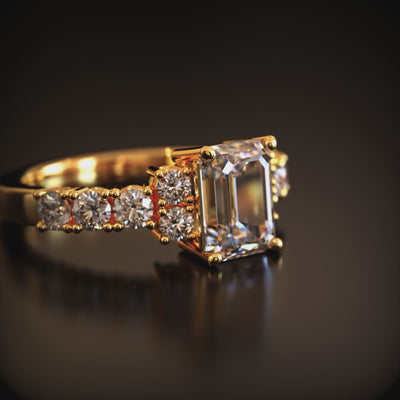 A solid gold ring with an emerald-cut moissanite center stone.