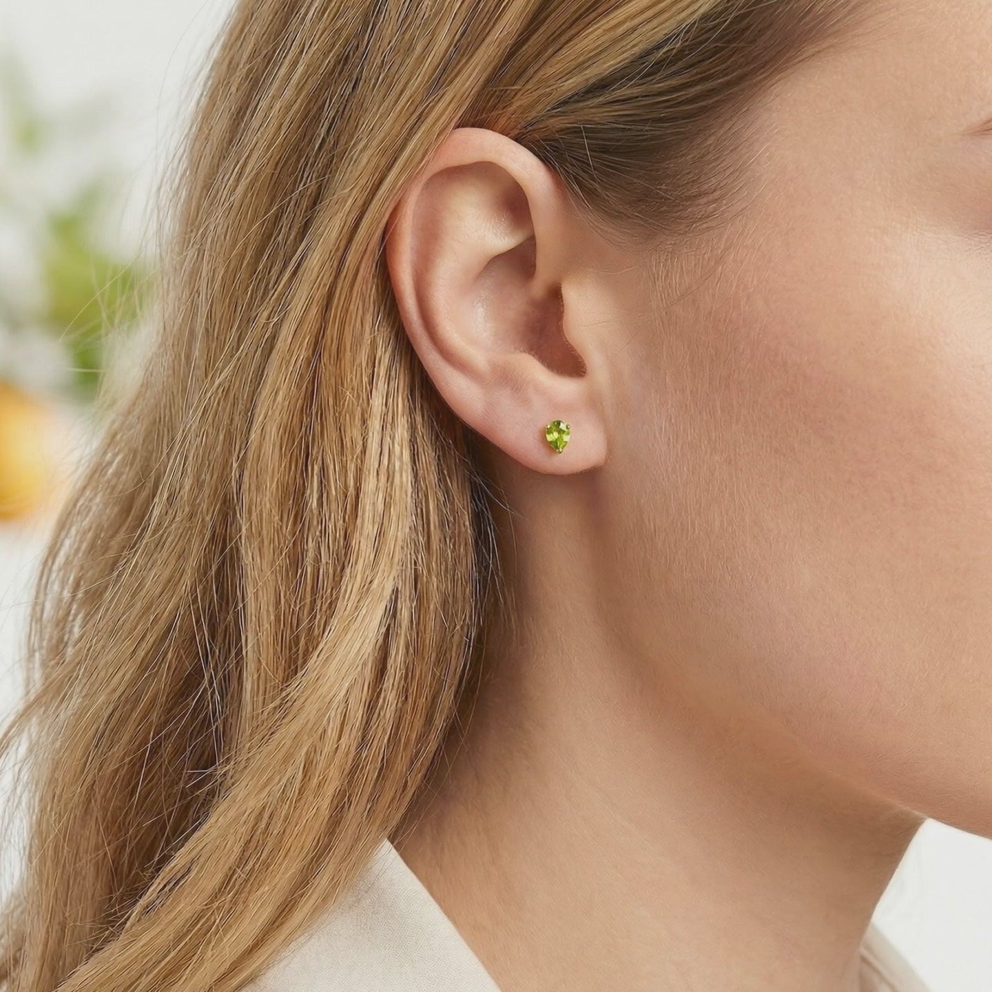 A pair of solid gold earrings with simulated peridot.