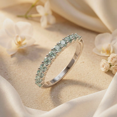 Close-up angled view of a silver eternity ring with round pale green simulated alexandrite stones.