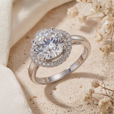 Close-up of the silver halo ring on a light textured surface beside dried flowers.