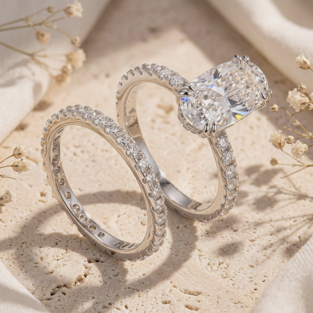 Oval center ring and matching pavé band displayed upright on a textured stone surface
