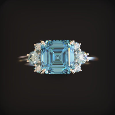 A solid gold ring with a blue moissanite.