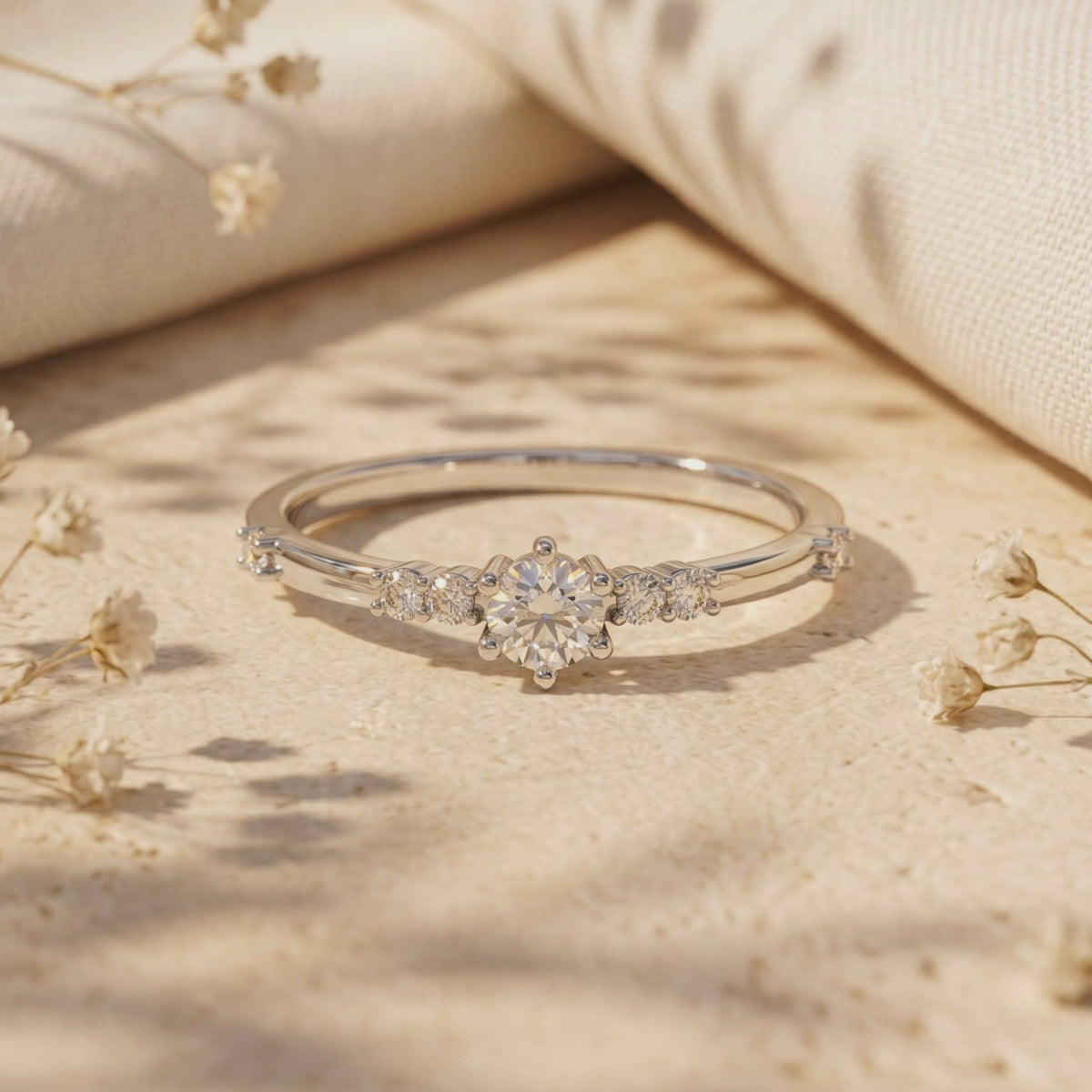 Silver-tone round moissanite ring with side accent stones displayed on a textured surface.