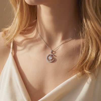 Silver crescent moon pendant necklace with a round center stone worn on a model's neck.