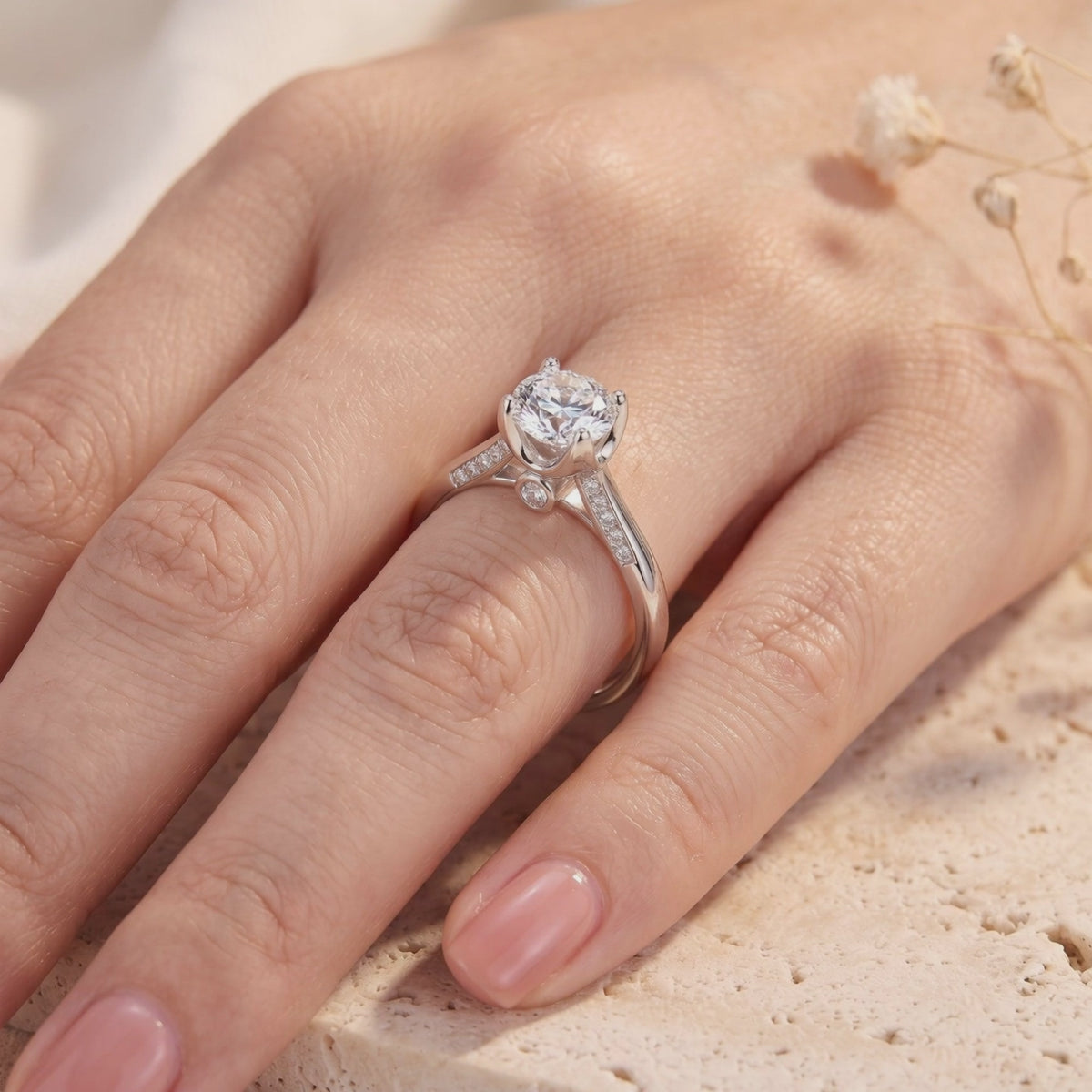 Silver solitaire ring with a round center stone and micro-pavé cathedral shoulders worn on a hand.