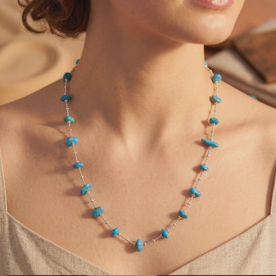 Turquoise nugget beads spaced along a silver chain, shown worn around a model’s neck and upper chest.