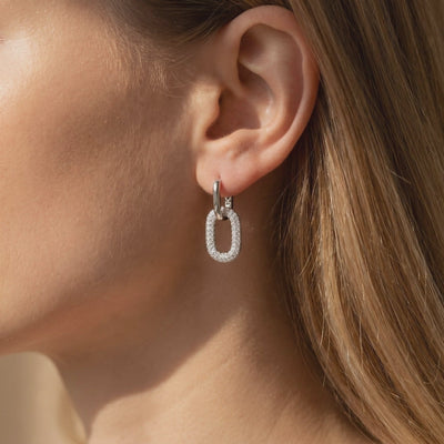 Model wearing a silver double-link drop earring with a pavé-set oval charm.
