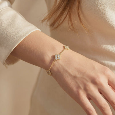 Gold moissanite clover station bracelet shown worn on a woman's wrist.