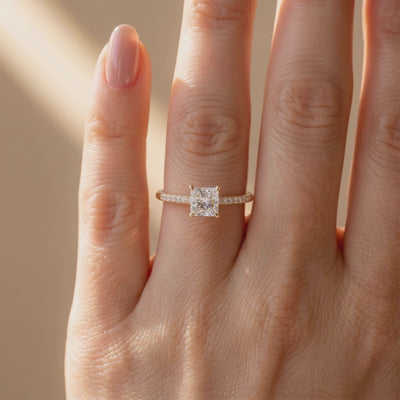 Princess-cut moissanite solitaire ring with a pavé band, shown worn on a hand.
