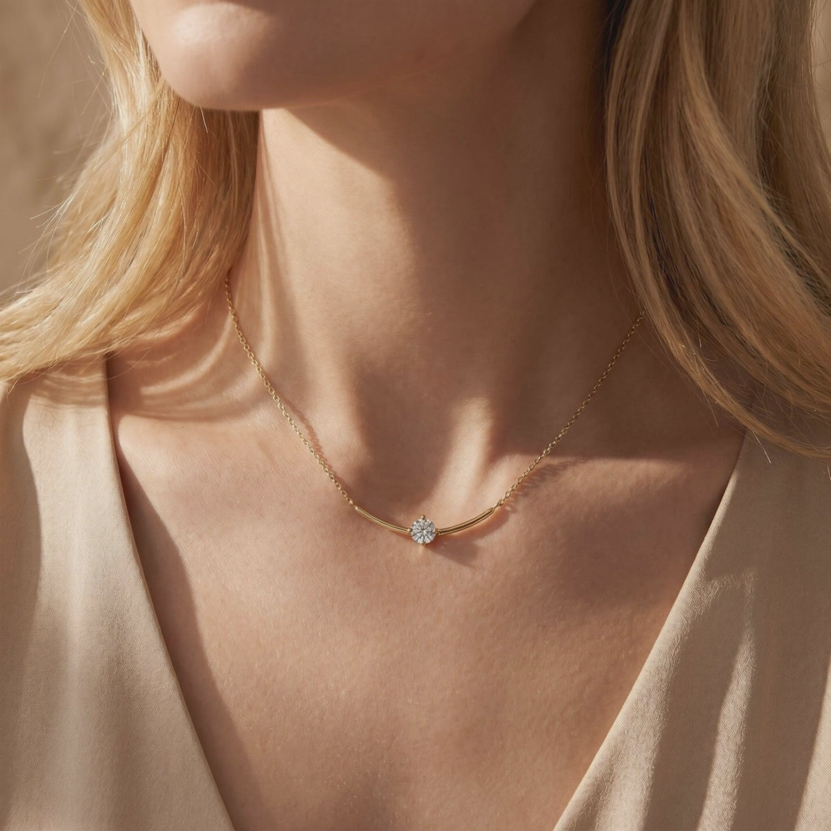 Gold-toned curved-bar moissanite necklace with a round center stone worn at a woman's collarbone.