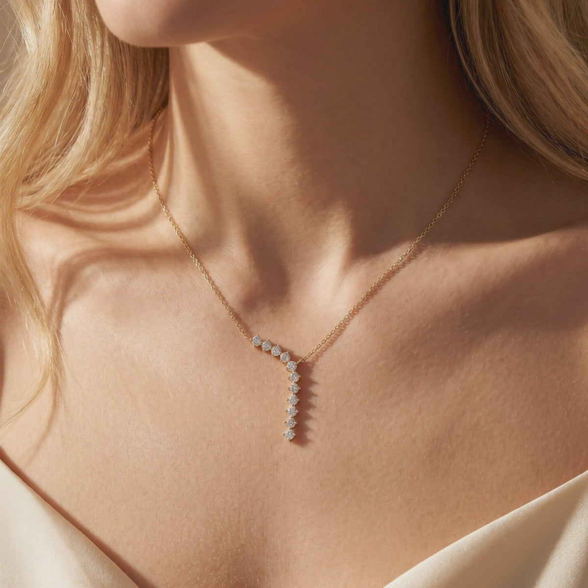 Gold-tone Y-necklace with cascading round white moissanite stones, shown worn on a model's neck.