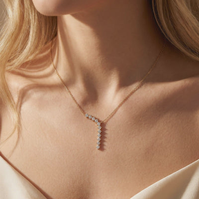 Gold-tone Y-necklace with cascading round white moissanite stones, shown worn on a model's neck.