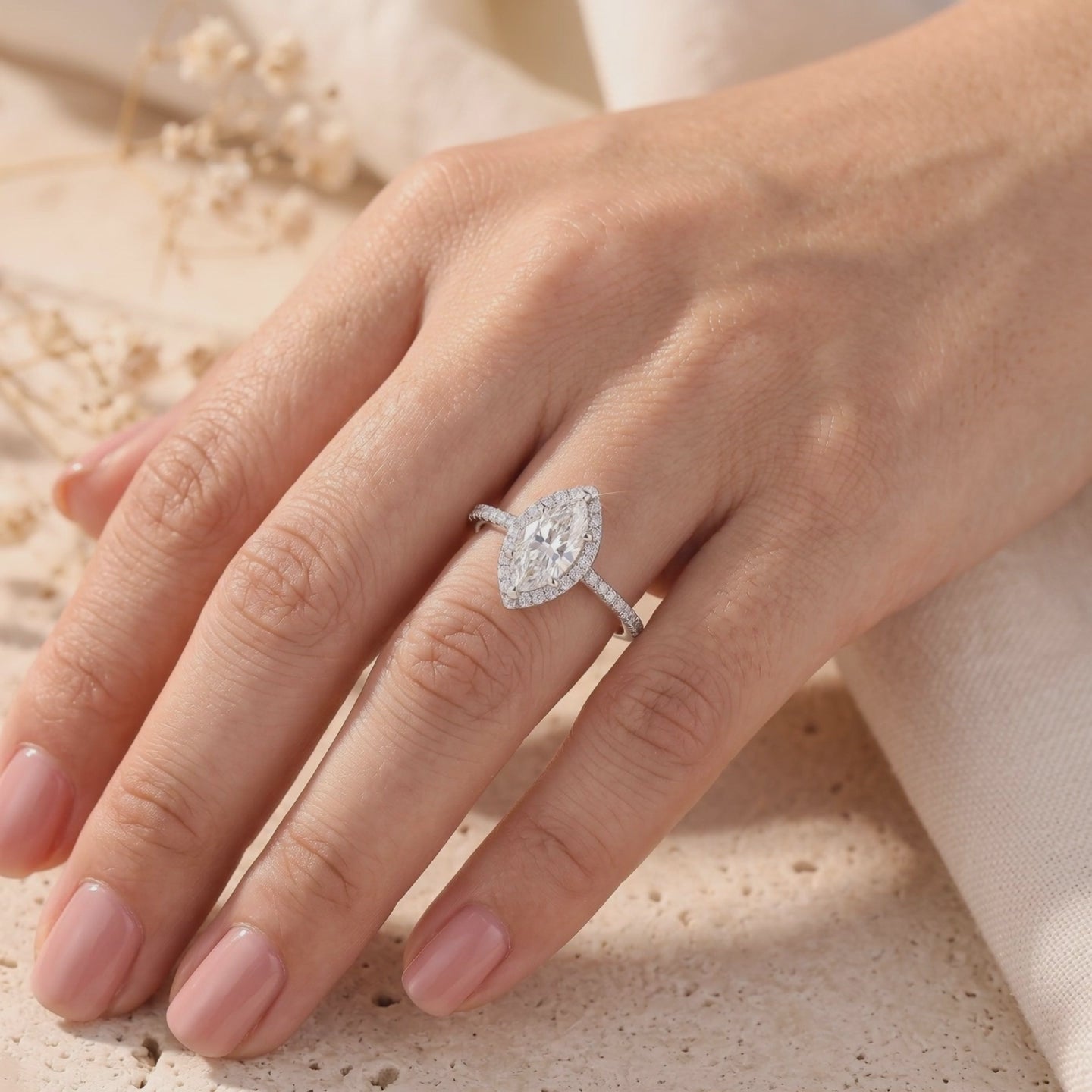 Silver marquise halo ring with micro-pavé band, shown worn on a hand.