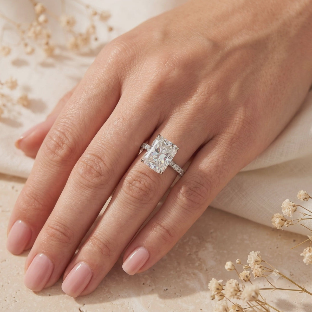 On-hand view of a silver ring with a large radiant-cut clear center stone and pavé band.
