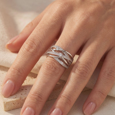 Interwoven silver crossover ring with cubic zirconia accents worn on a hand's ring finger.