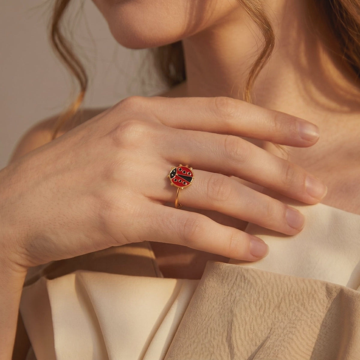 Gold-tone bypass ring with a red and black enamel ladybug, shown worn on a model's finger.