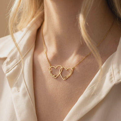 Gold-toned interlocking heart necklace with Amanda and Daniel, worn at the neck.