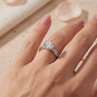 Silver ring with a large round clear stone and twisted pavé band worn on a hand.