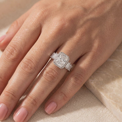 Silver cushion-cut halo ring with baguette accents worn on a ring finger