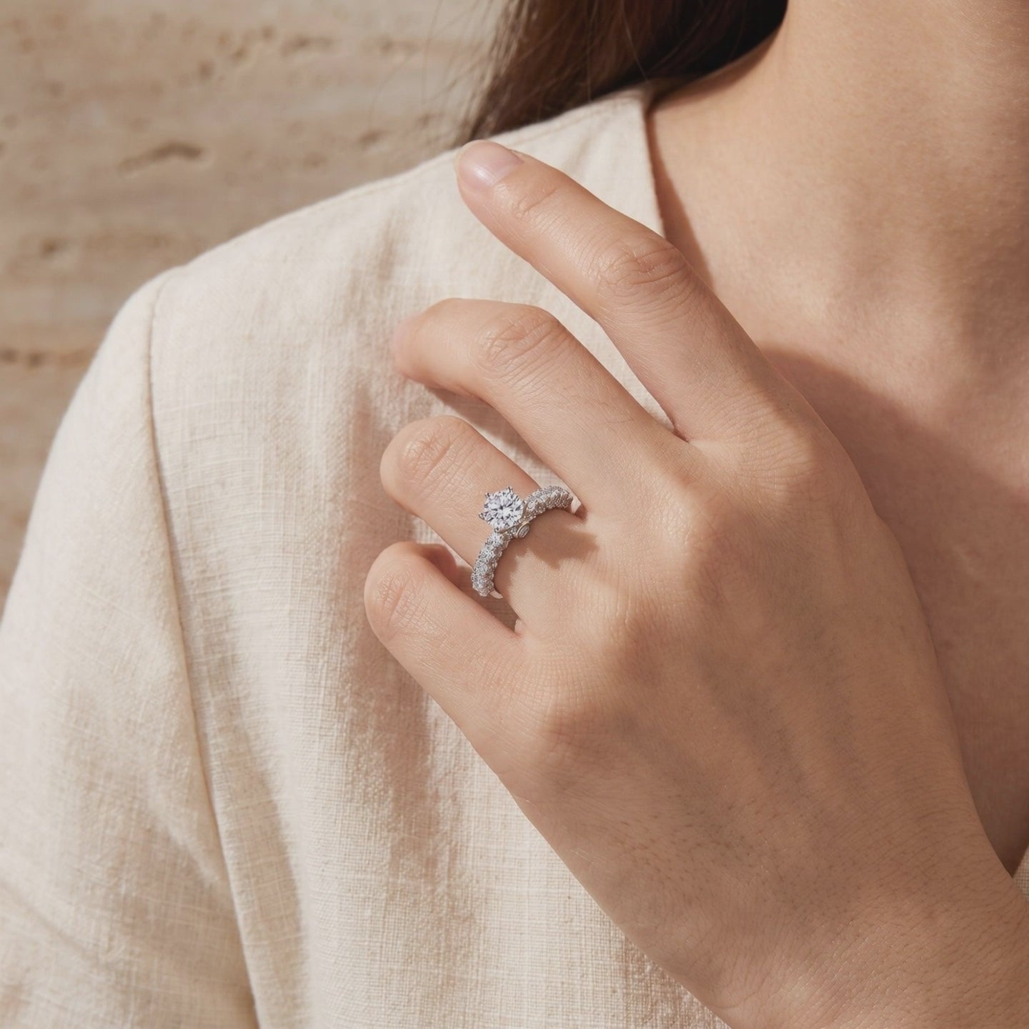 Silver cathedral ring with a round center stone worn on a hand against light fabric.