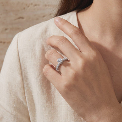 Silver cathedral ring with a round center stone worn on a hand against light fabric.
